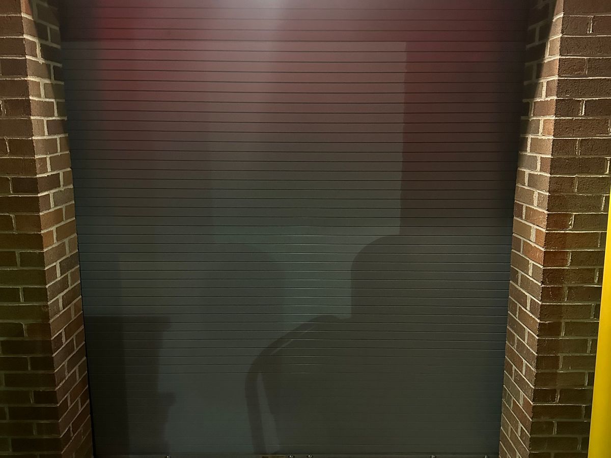 Commercial rolling steel door installed in brick opening at parking structure