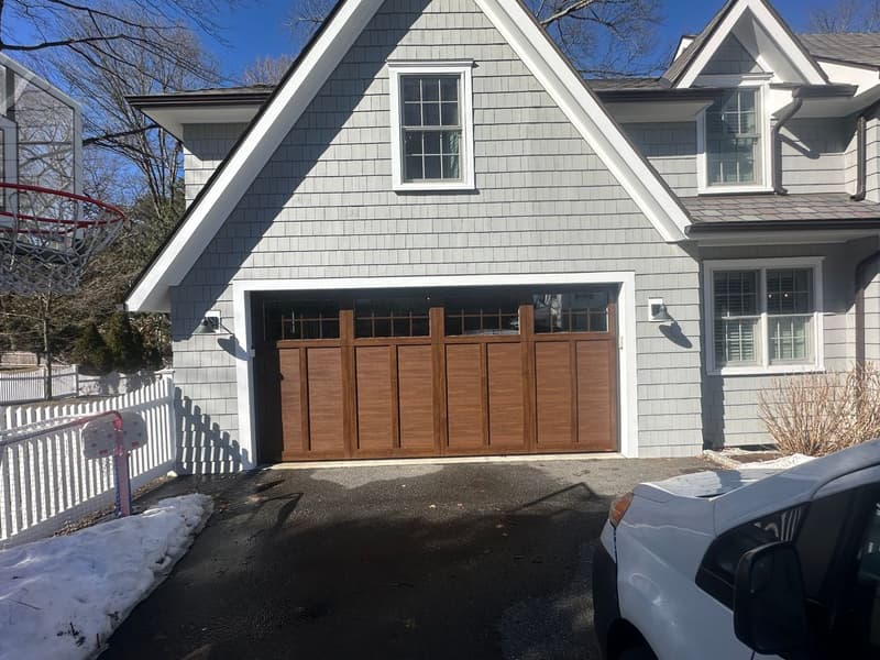 Beautiful craftsman-style wood garage door installation on gray shingle home